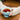 Hands cupping a blue teacup, wearing a pair of beige cabled mitts.