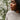 Close up of Joy, our model, wearing a One Sweater in an oatmeal colour. She is gazing to the side with lots of vines behind her.