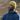 A man looking away from the camera is standing on the fells in Cumbria wearing a hand knitted mock cable beanie hat and hoodie