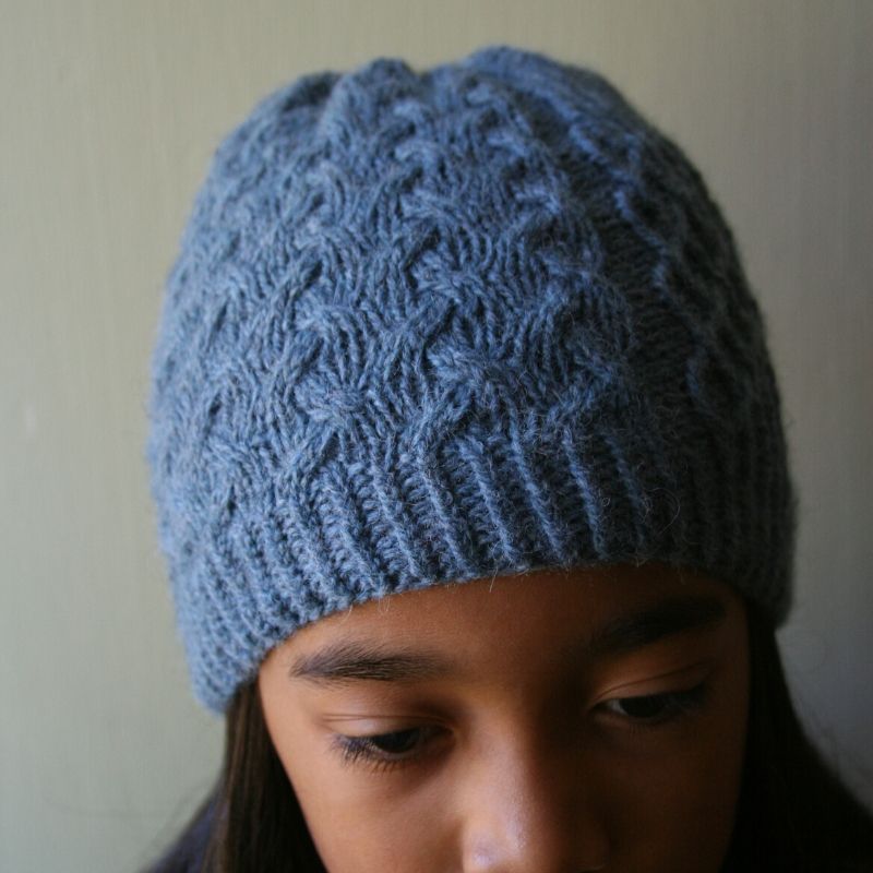 Heavily cabled, pale blue hat with a twisted rib brim.